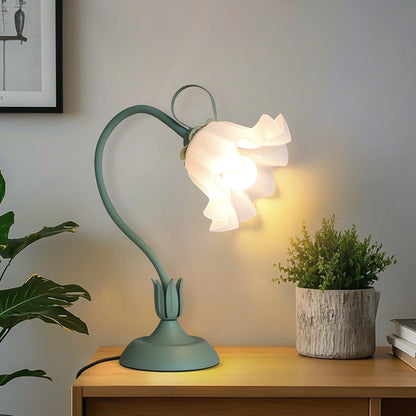 Flower table lamp with frosted glass petal shade glowing warm on a console table