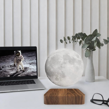 floating moon lamp on minimalist desk with laptop and eucalyptus plant